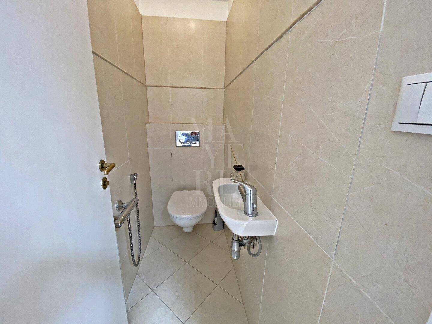Kleines Gäste-WC mit wandhängender Toilette und kompaktem Waschbecken, komplett gefliest.