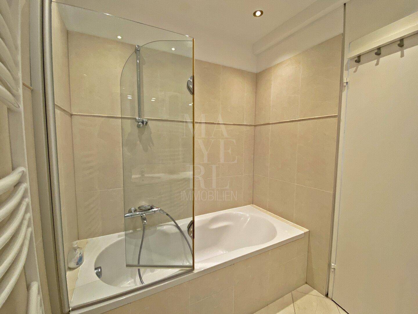 Gefliestes Badezimmer mit Badewanne und praktischer Glasduschwand für Komfort.