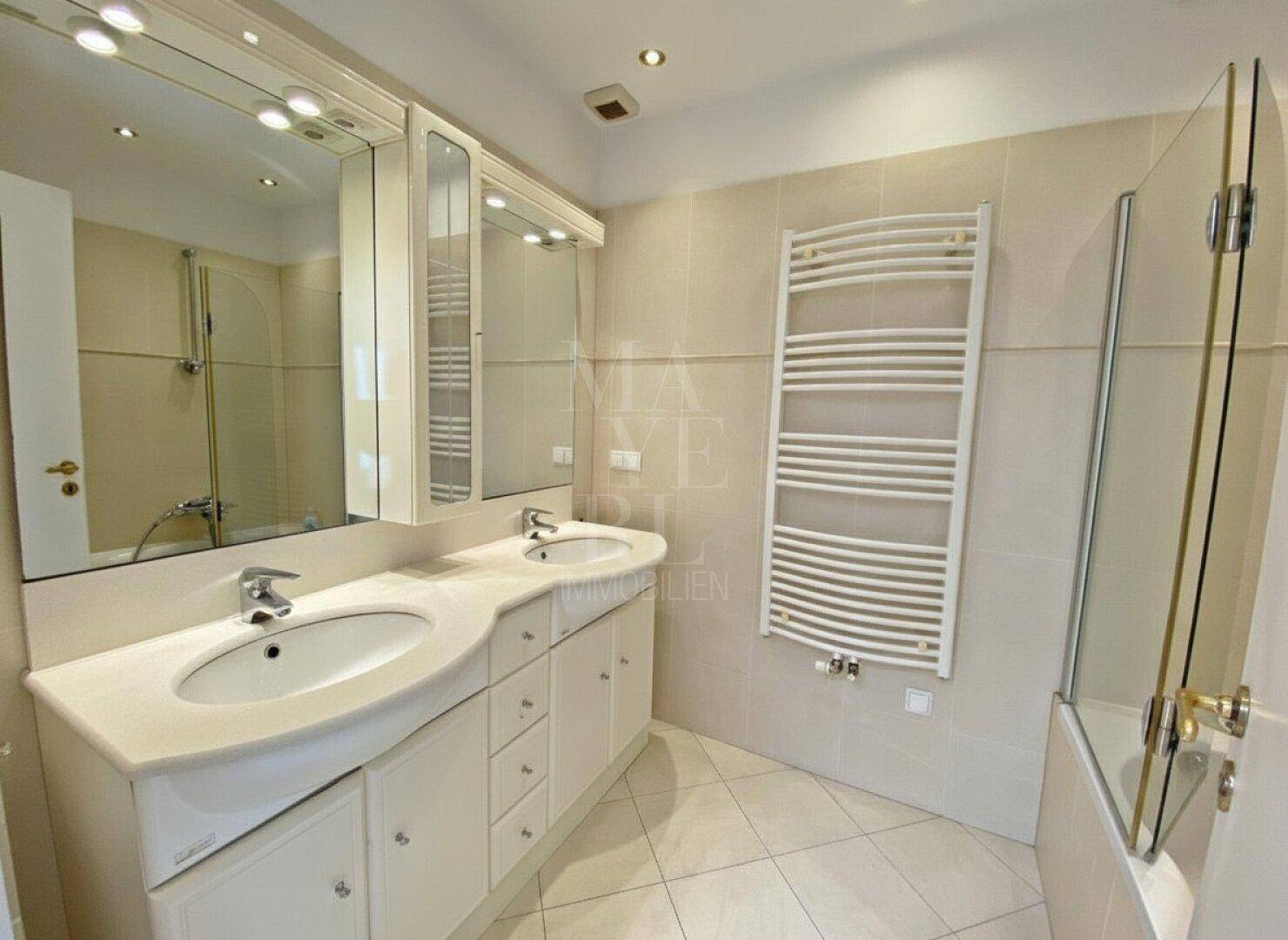 Modernes Badezimmer mit Doppelwaschbecken, großem Spiegel und beheiztem Handtuchhalter.