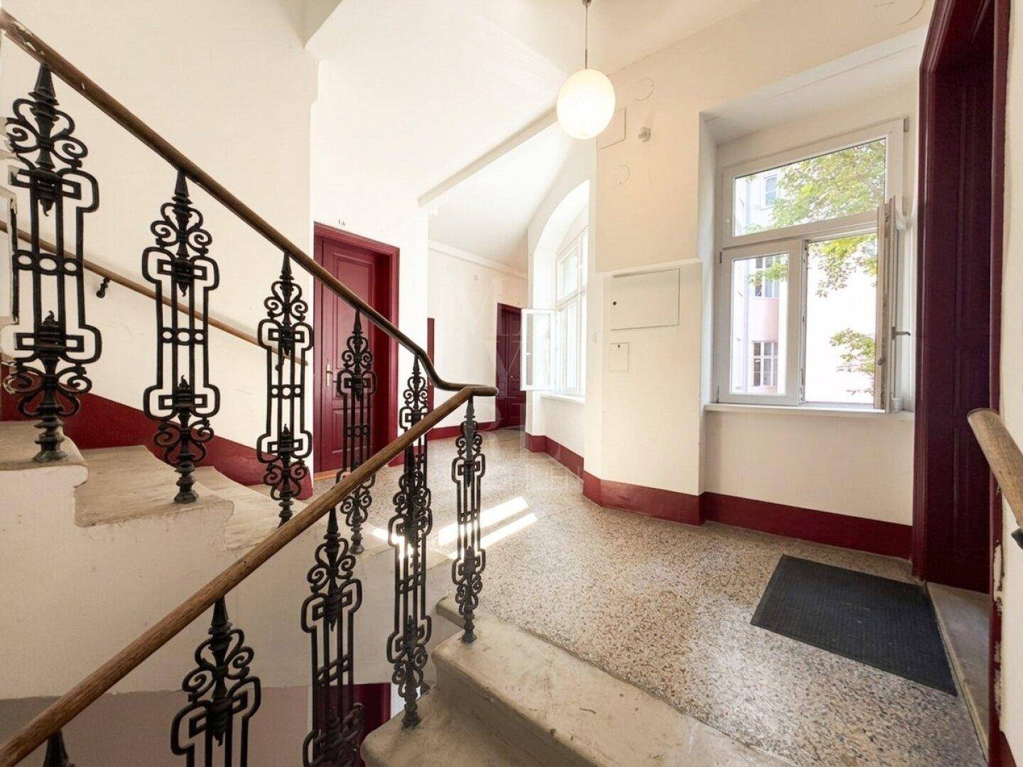 Historisches Treppenhaus mit schmiedeeisernem Geländer und Terrazzoboden in einem Altbau.