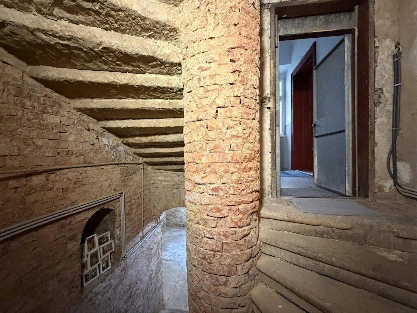 Historische Wendeltreppe aus Ziegelstein im Kellerbereich eines alten Gebäudes.
