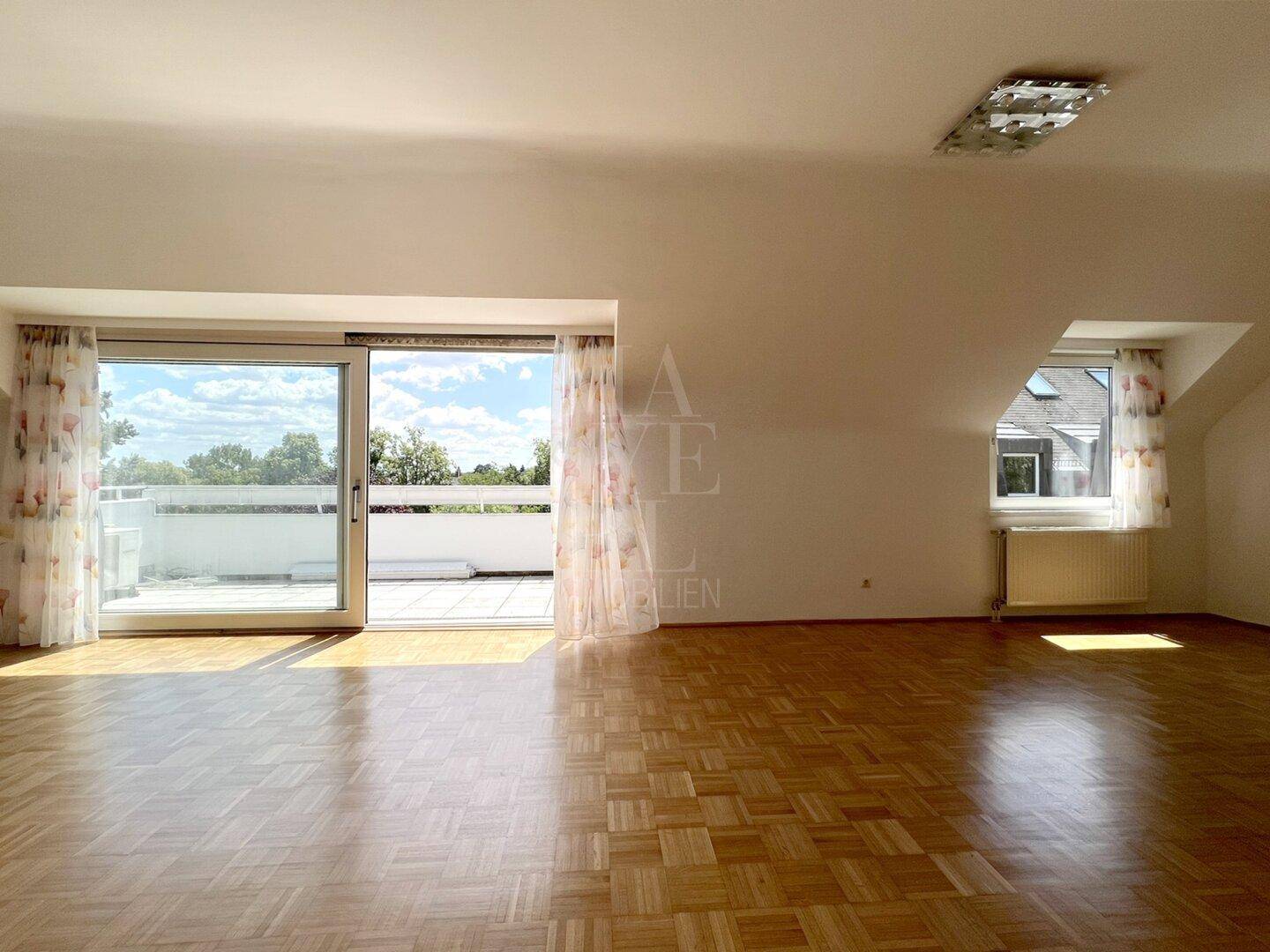 Lichtdurchflutetes Wohnzimmer mit Parkettboden und breiter Schiebetür zur Dachterrasse.