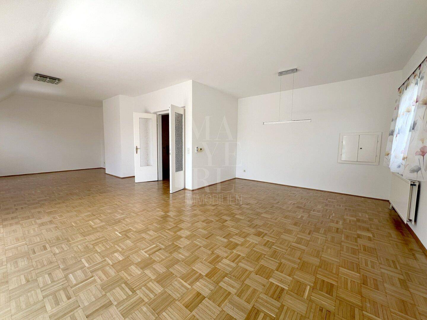 Geräumiges Wohnzimmer mit Parkettboden und weißen Wänden, bereit zur individuellen Gestaltung.