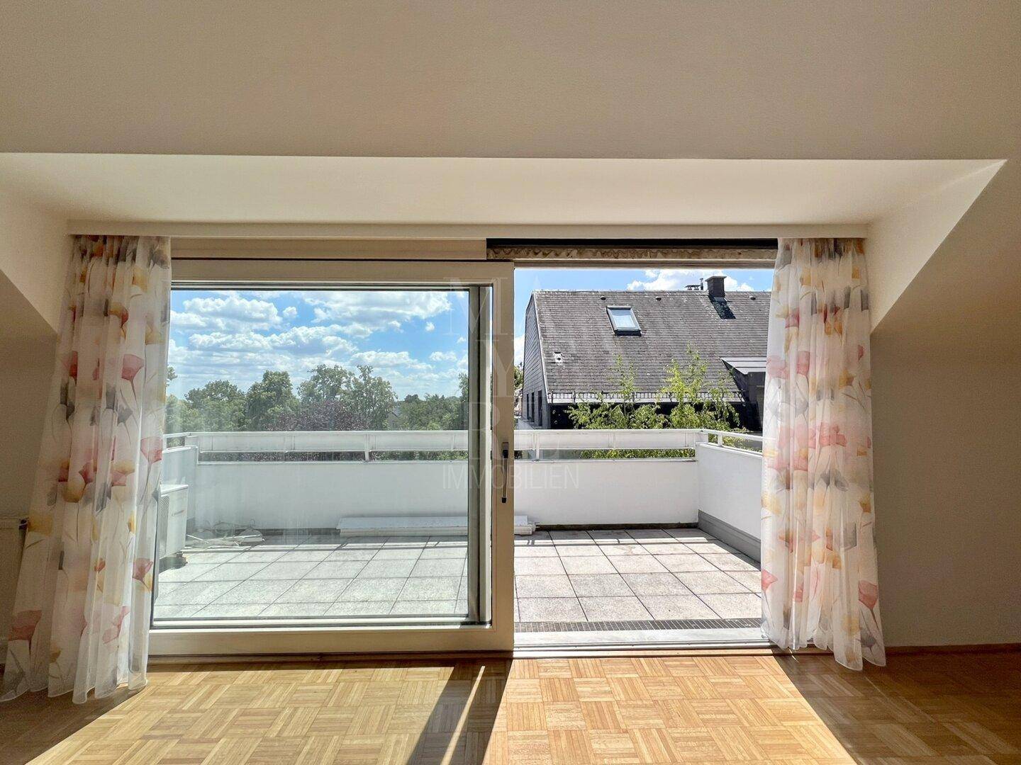 Heller Wohnraum mit Parkettboden und großem Terrassenzugang, der viel Licht hereinlässt.