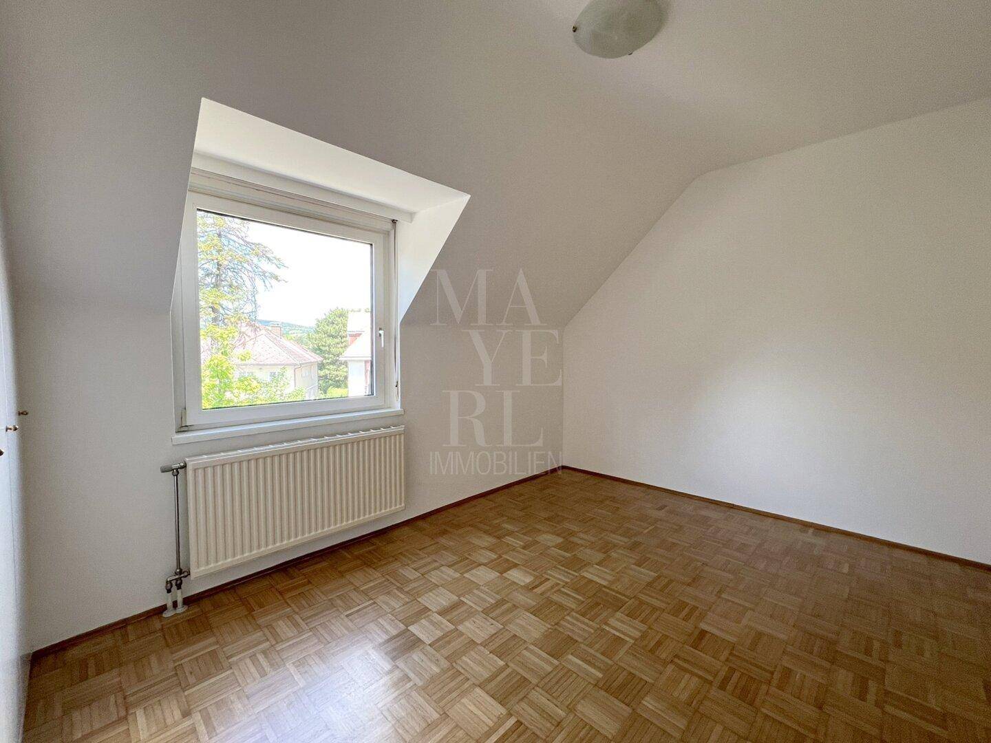 Geräumiges Schlafzimmer mit Parkettboden, Dachschräge und Fenster, das viel Licht spendet.