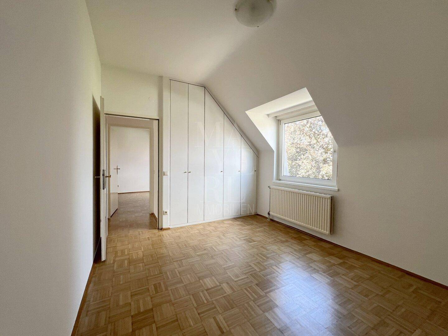 Schlafzimmer mit Parkettboden, Dachschräge und praktischen Einbauschränken für Stauraum.