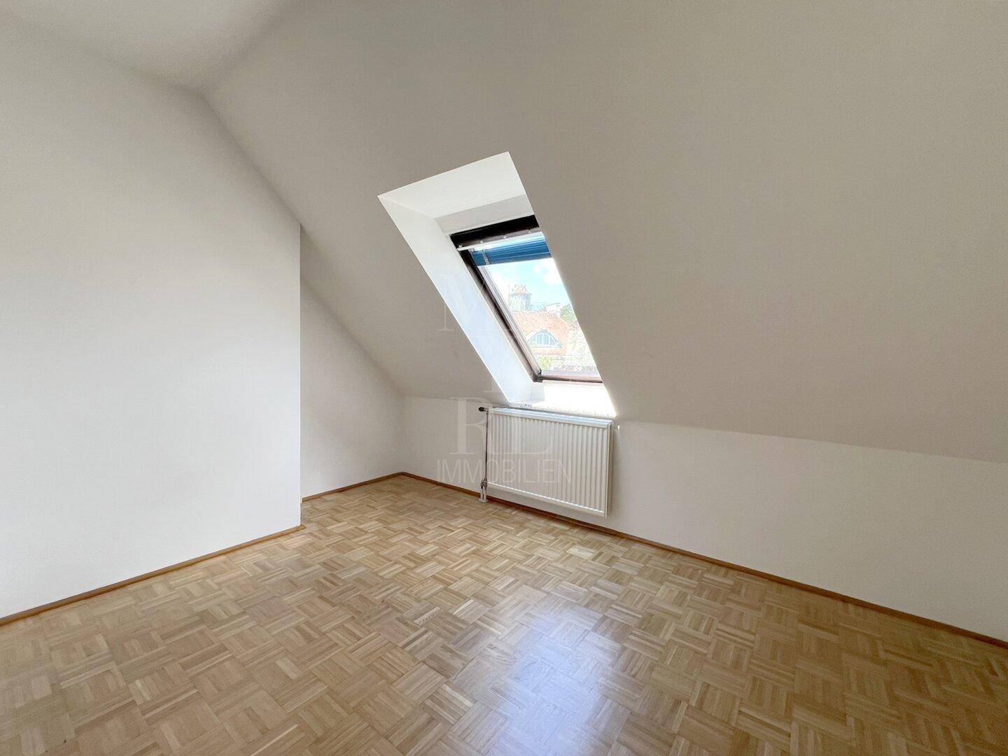 Helles Zimmer mit Parkettboden, Dachschräge und Dachfenster, ideal als Kinder- oder Gästezimmer.