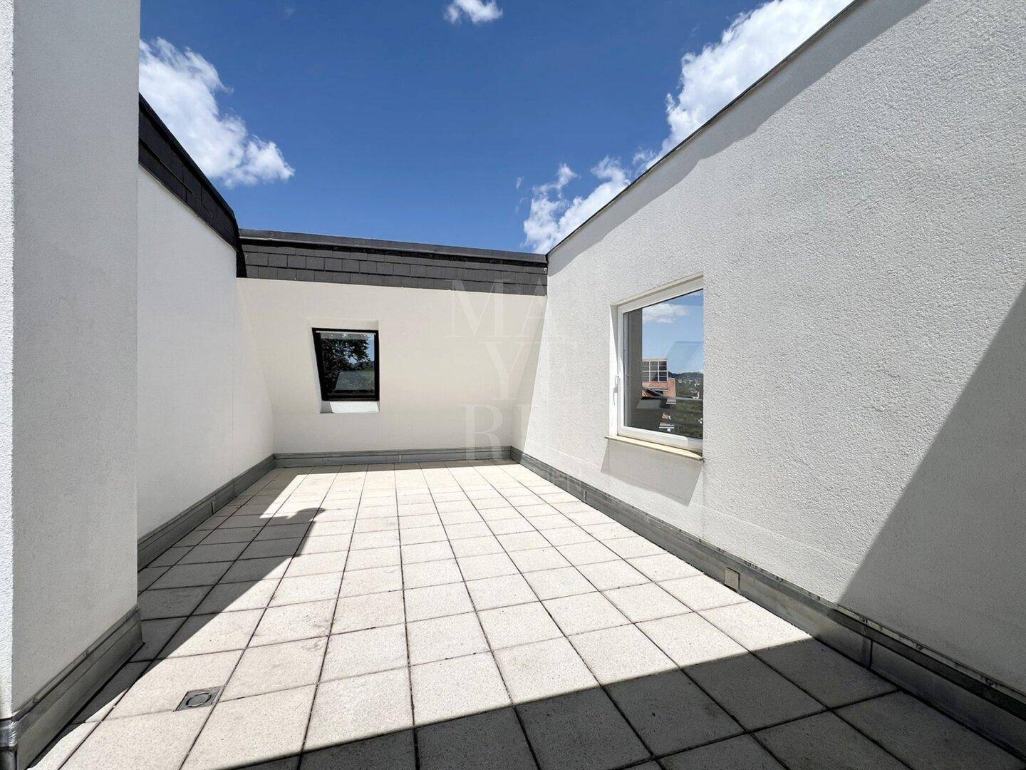Weitläufige Dachterrasse mit Fliesenboden und hohen Wänden, die Privatsphäre bieten.