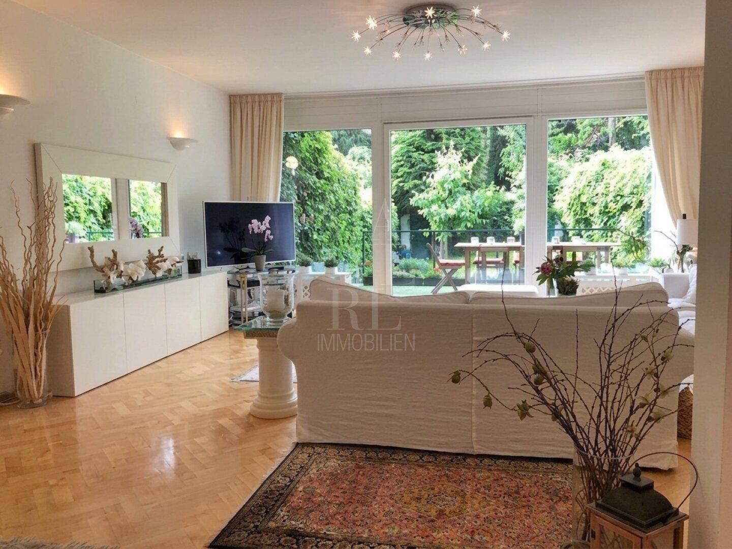 Lichtdurchflutetes Wohnzimmer mit bequemer Couch und direktem Blick sowie Zugang zur Gartenterrasse.