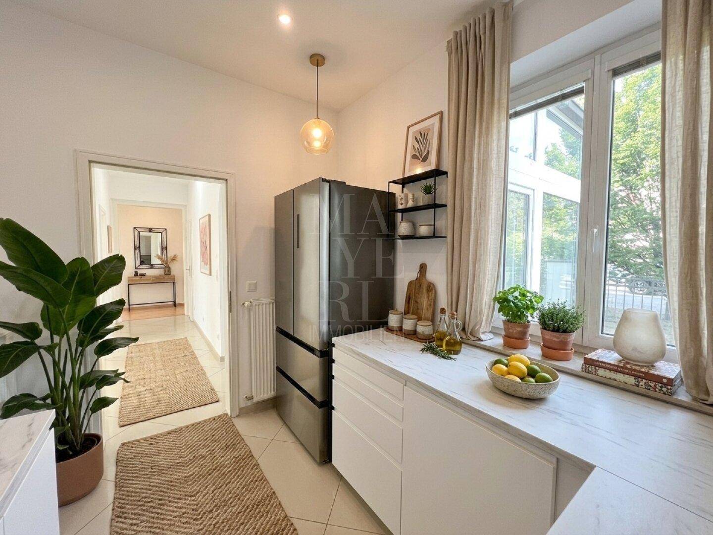 Küchenbereich mit großem Kühlschrank, Fenster und Blick in den angrenzenden Flur.