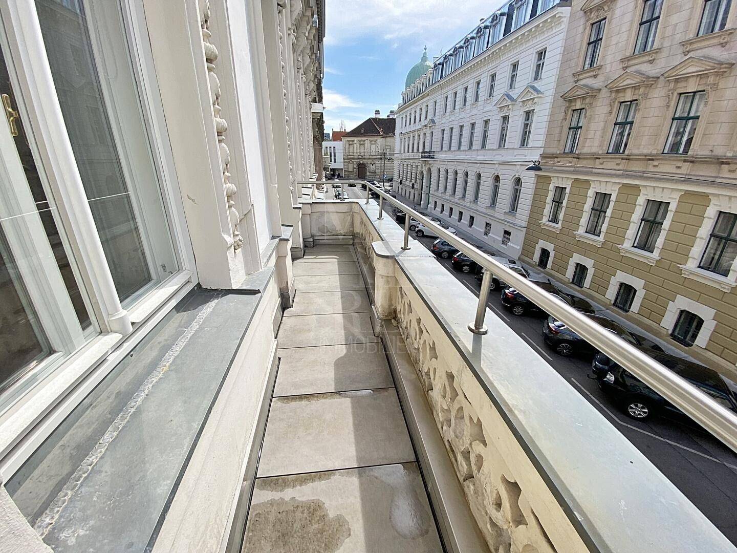 Langer schmaler Balkon mit schmiedeeisernem Geländer und Blick auf die Stadtstraße.