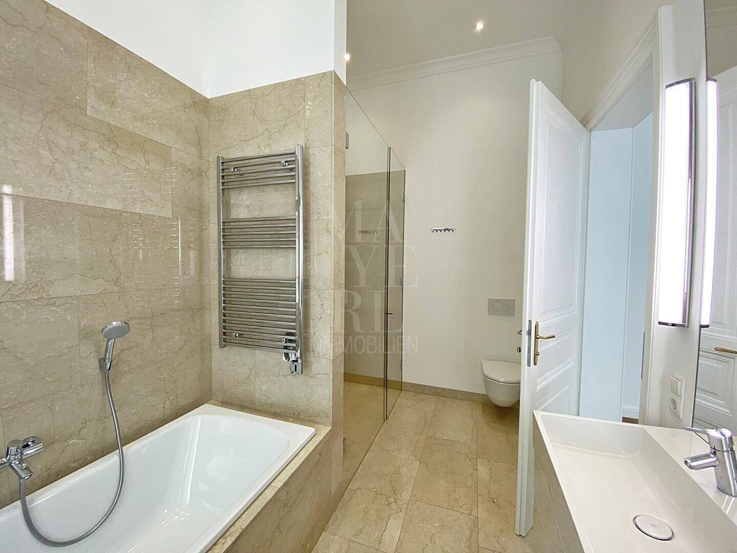 Elegantes Badezimmer mit Badewanne, Duschbereich, WC und beheiztem Handtuchhalter.