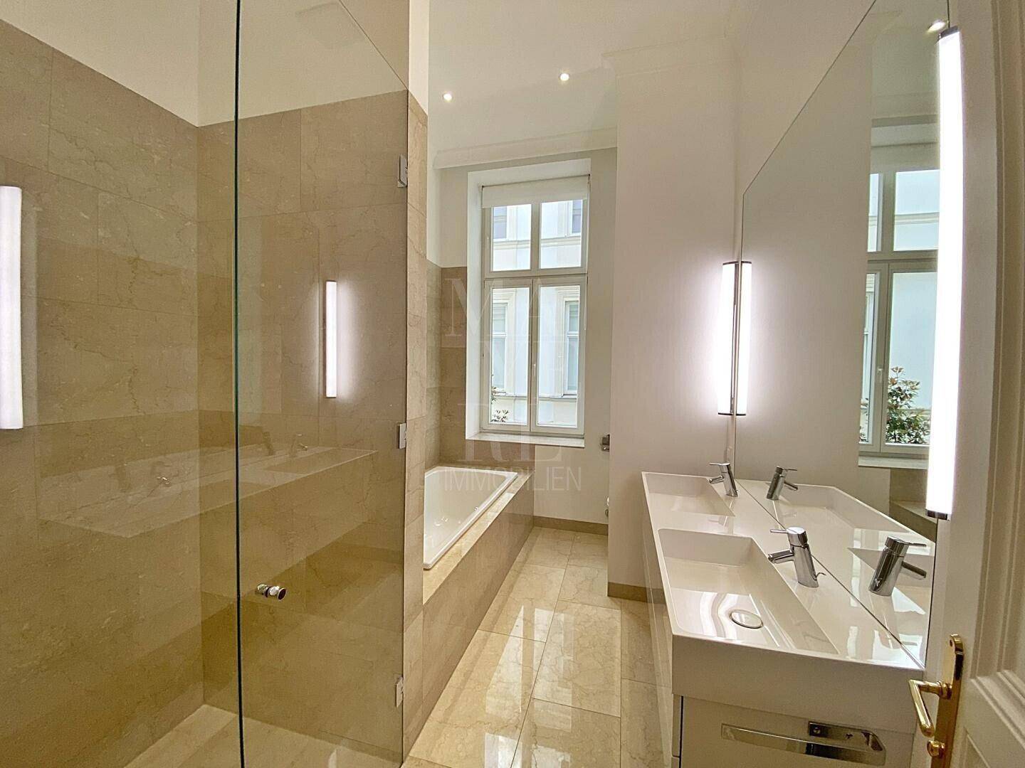 Modernes Badezimmer mit Doppelwaschbecken, Badewanne und großer Glasdusche.
