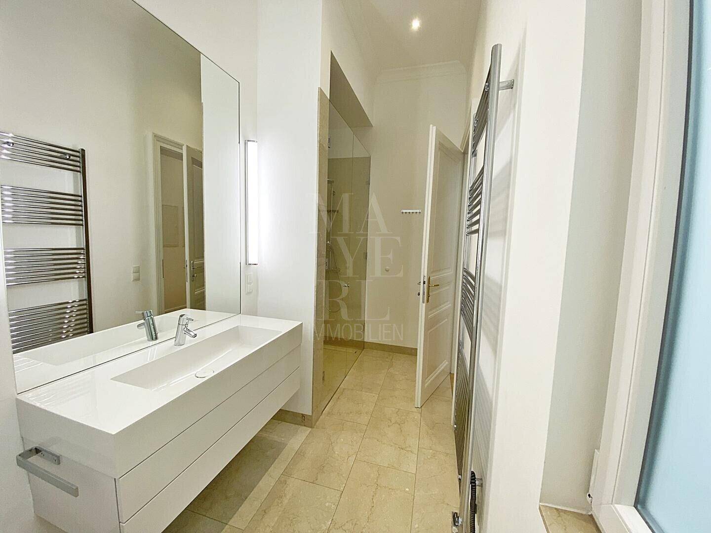 Modernes Badezimmer mit Einzelwaschbecken, großem Spiegel und beheiztem Handtuchhalter.