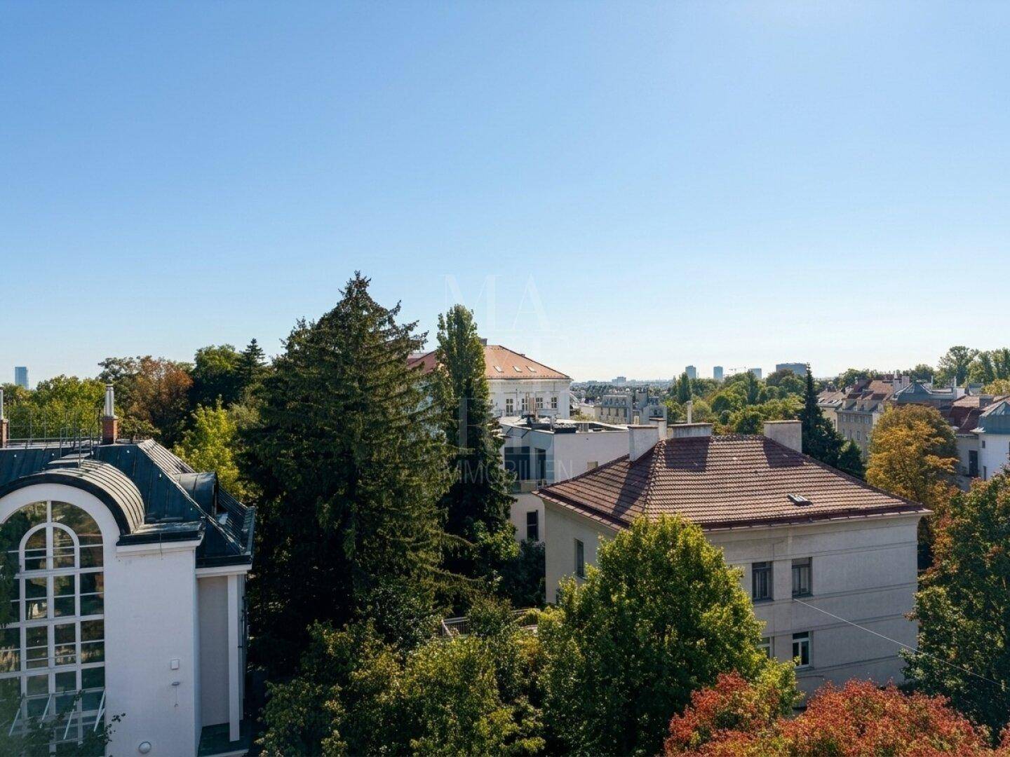 Panoramablick über die Stadt mit grünen Bäumen und historischen Gebäuden unter blauem Himmel.