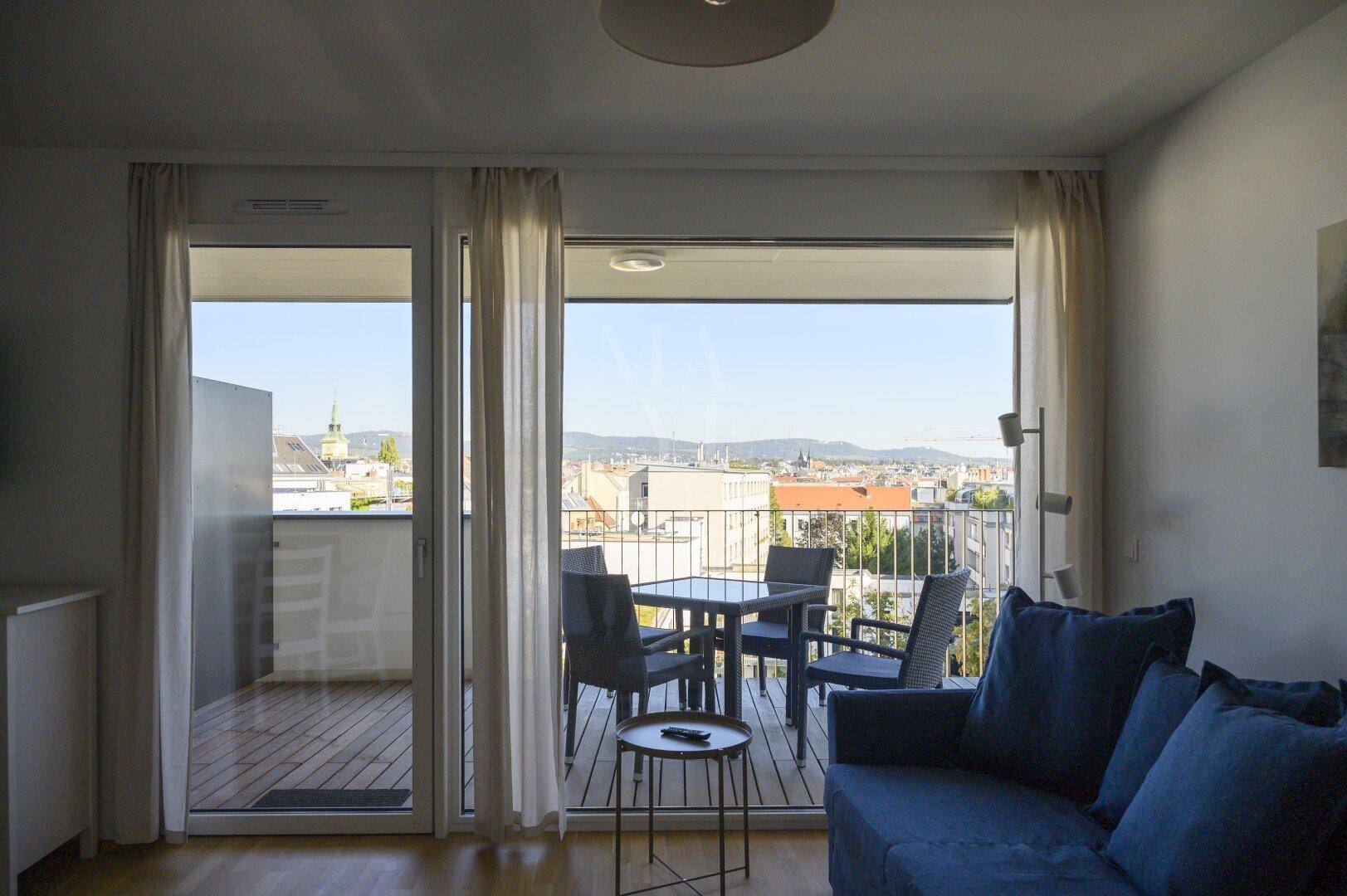 Heller Wohnbereich mit großem Balkonzugang und weitem Blick über die Stadtlandschaft.