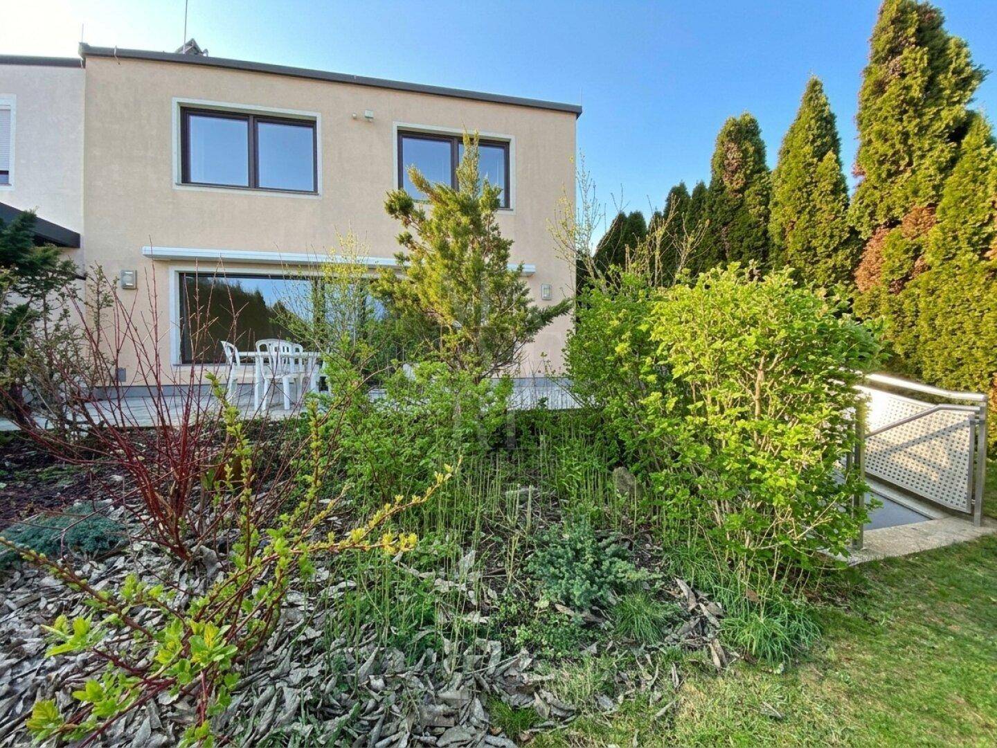 Hinterer Terrassenbereich mit Gartenmöbeln und Blick auf die grüne Umgebung.