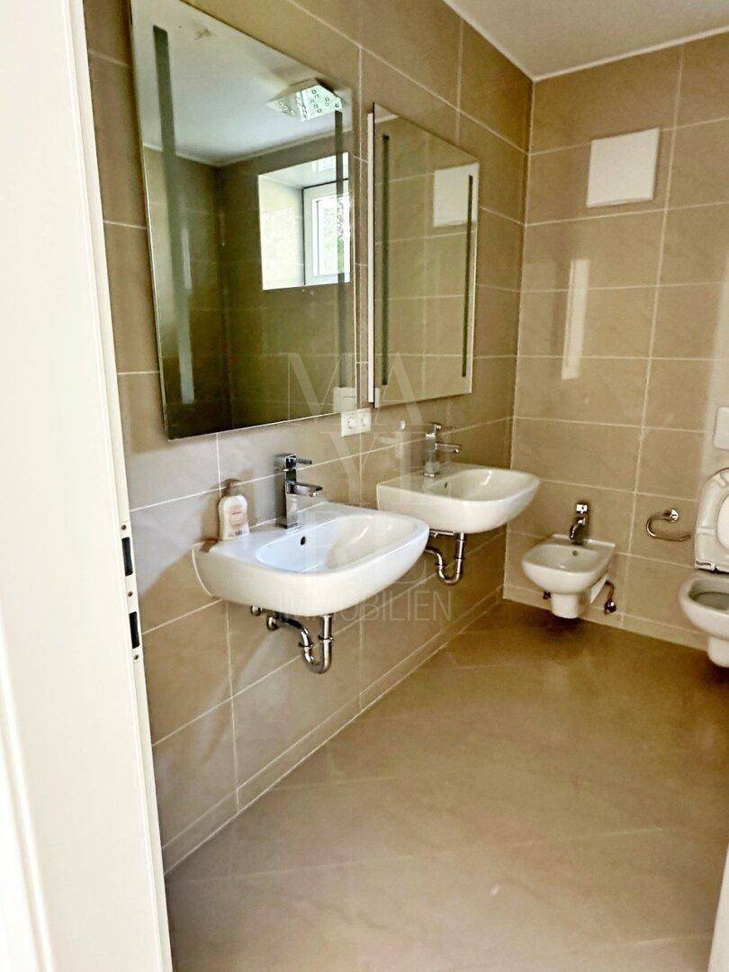 Modernes Badezimmer mit zwei Waschbecken, Bidet und großem Spiegel über den Waschtischen.