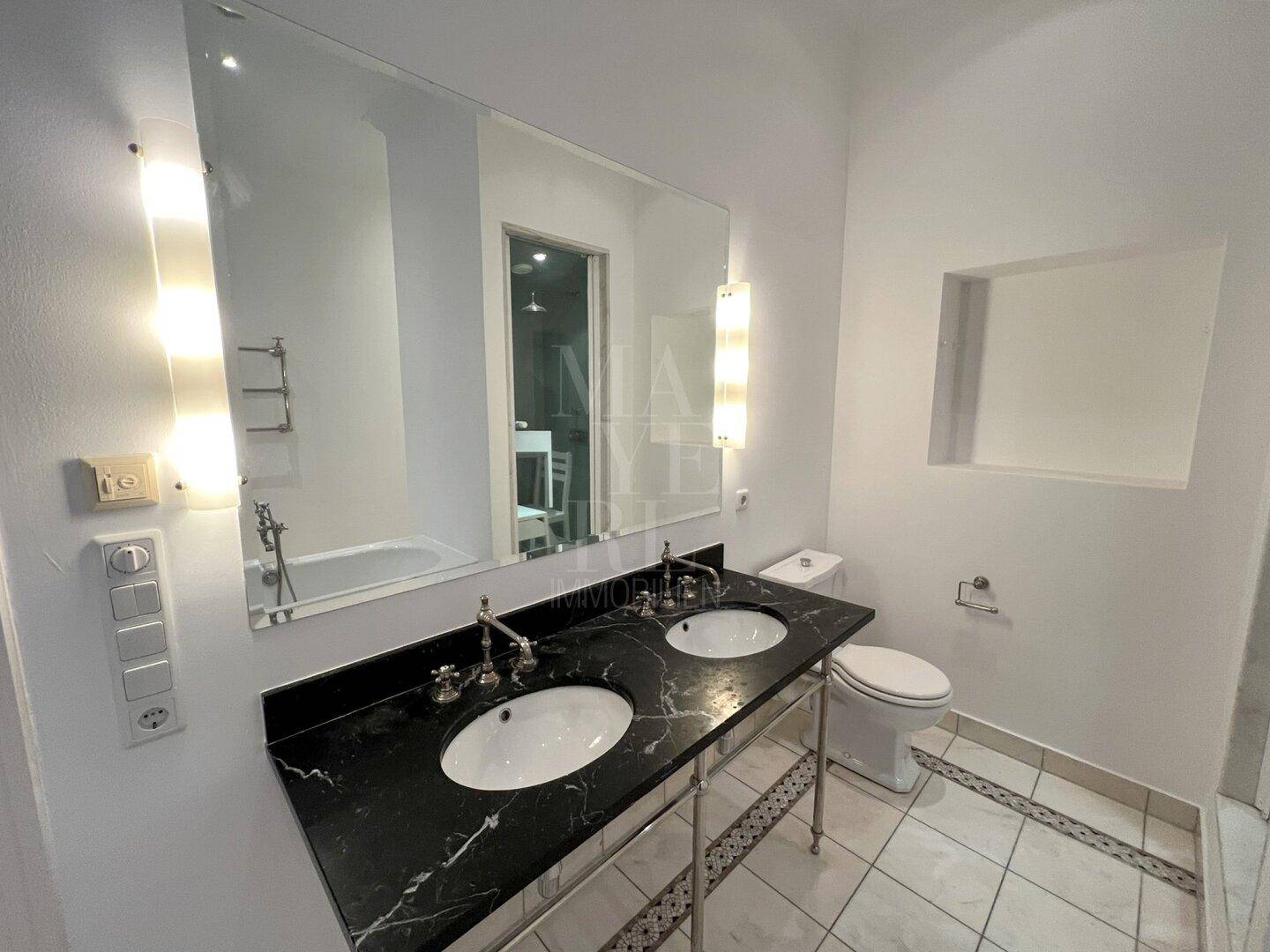 Stilvolles Doppelwaschbecken mit schwarzer Marmorplatte und großem Spiegel im luxuriösen Badezimmer.