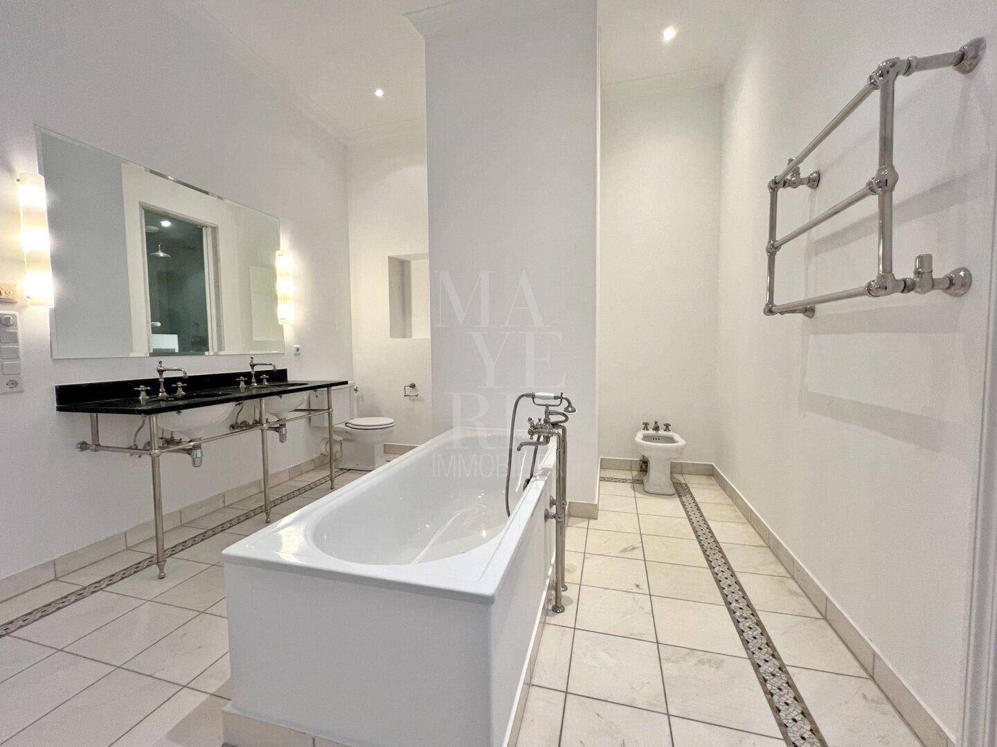 Elegantes Badezimmer mit freistehender Badewanne, Doppelwaschbecken und luxuriösen Marmoroberflächen.