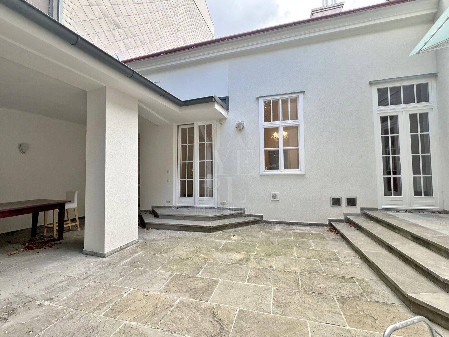 Geräumige Steinterrasse mit Zugang zum Haus, ideal für entspannte Stunden im Freien.