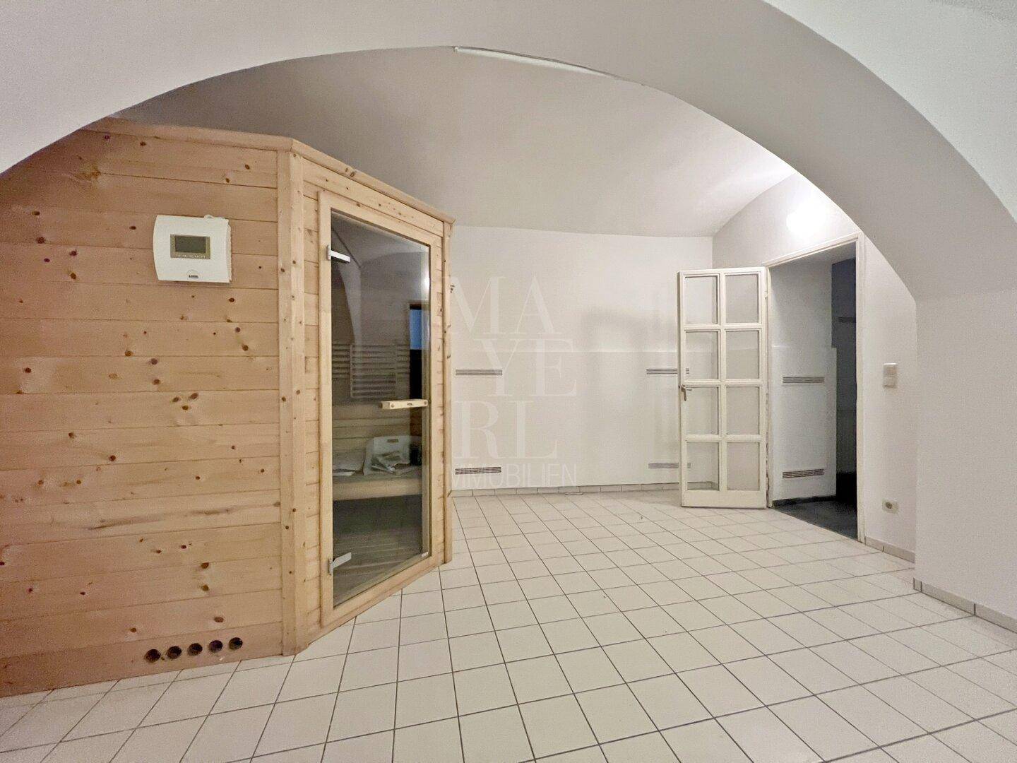Entspannungsbereich mit einer Holzsauna und gefliestem Boden unter einem eleganten Gewölbedach.