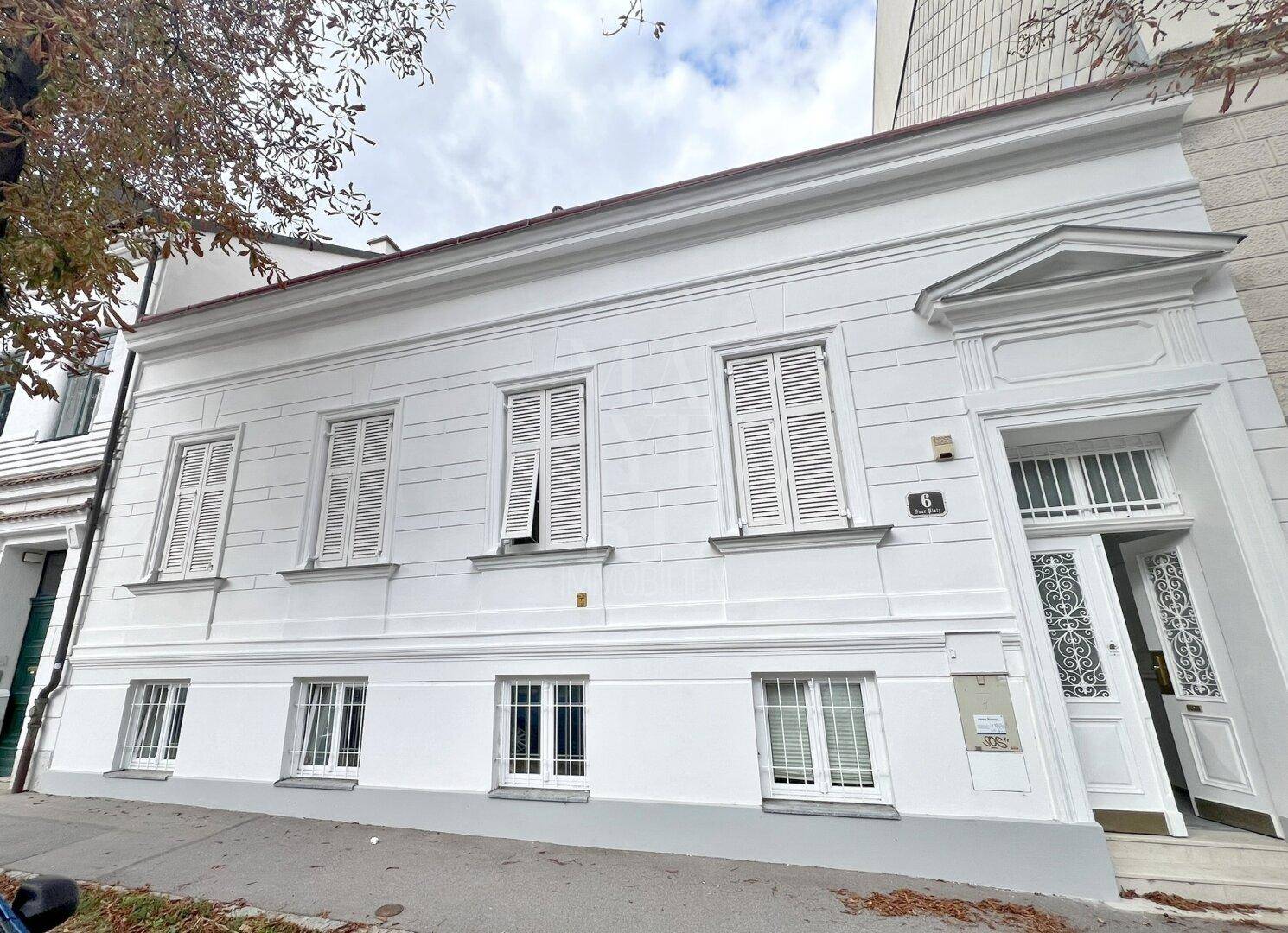 Klassisches weißes Gebäude mit traditionellen Fensterläden und eleganter Fassade in der Stadt.