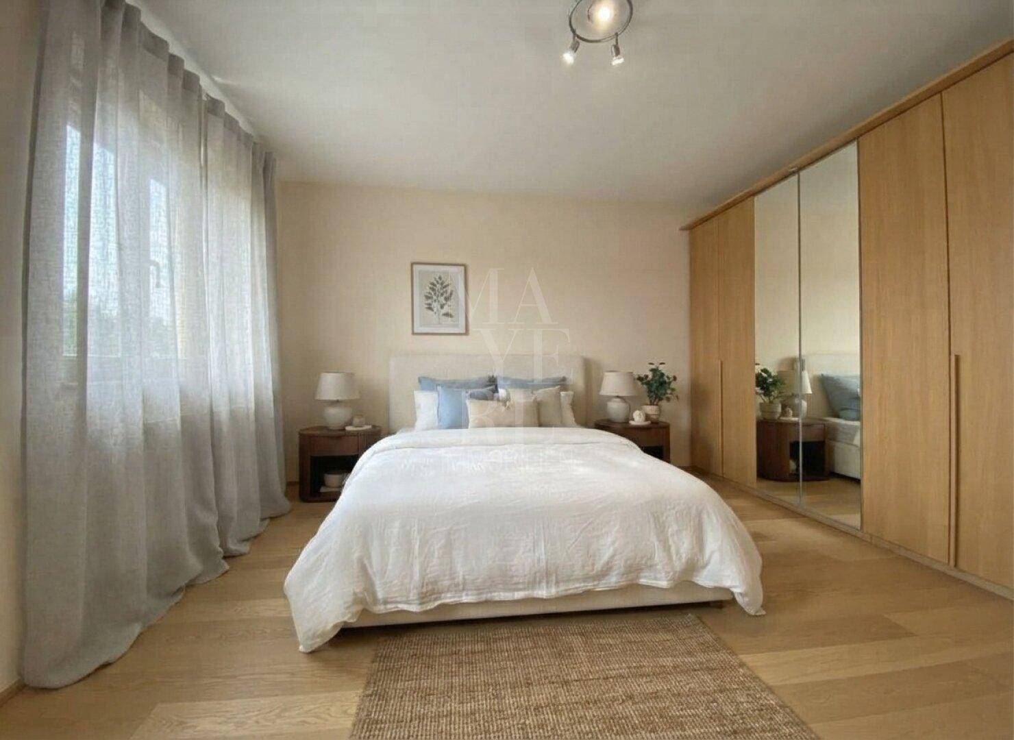 Helles Schlafzimmer mit Holzboden, großem Bett und Spiegelschränken, die den Raum optisch vergrößern.