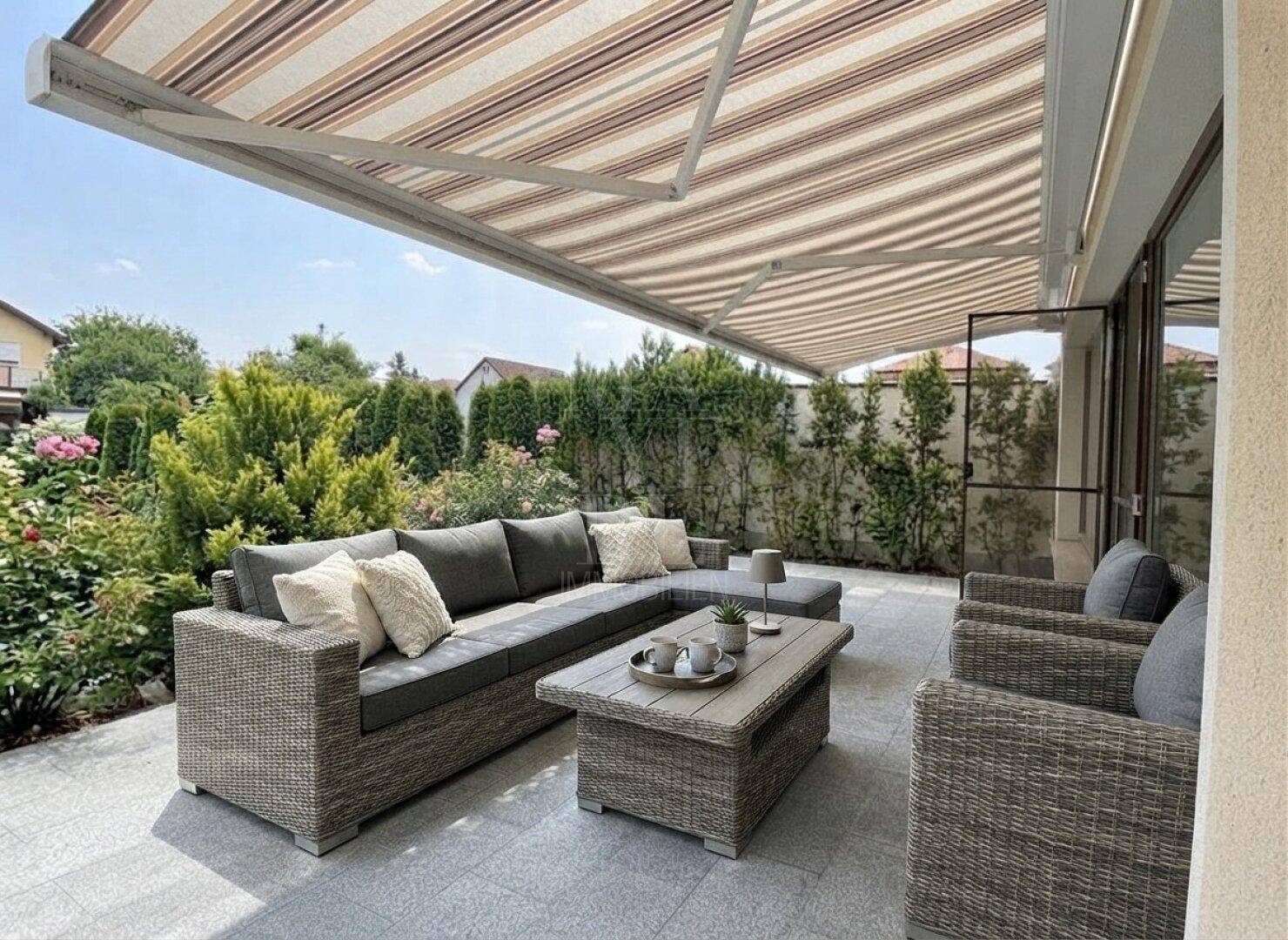 Geräumige Terrasse mit bequemen Loungemöbeln, Markise und umgebendem Grün für entspannte Stunden.
