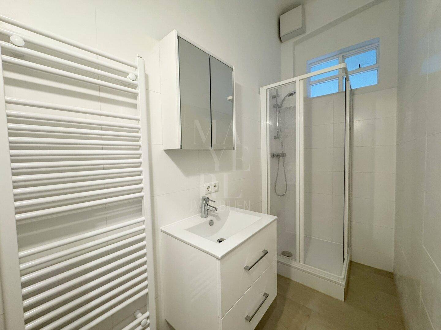 Modernes Badezimmer mit Duschkabine, Waschtisch, Spiegelschrank und beheiztem Handtuchhalter.