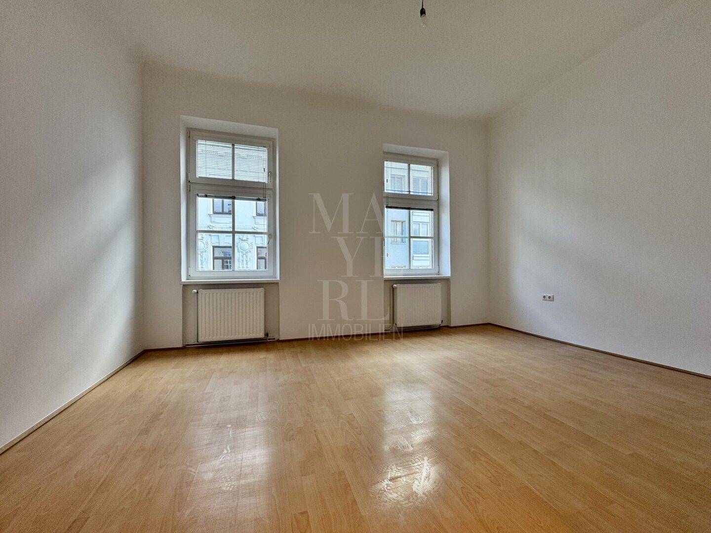 Helles und geräumiges Zimmer mit Parkettboden und zwei Fenstern, vielseitig nutzbar.