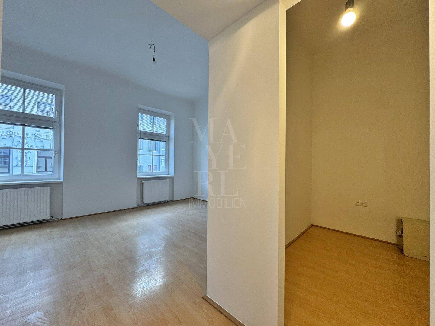 Heller Flur mit Zugang zu einem weiteren Zimmer, das ebenfalls über zwei Fenster verfügt.