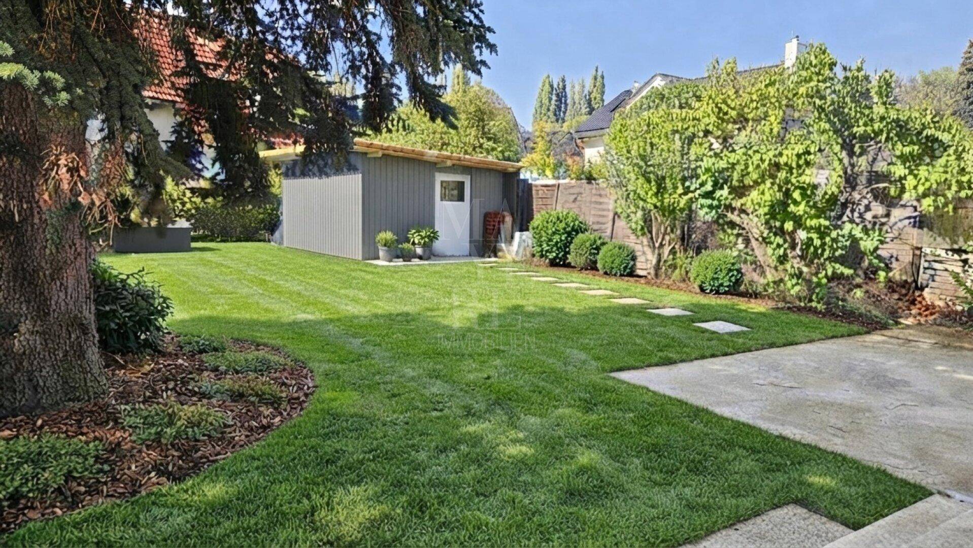 Gepflegter Gartenbereich mit Rasenfläche, einem Gartenhaus und altem Baumbestand.