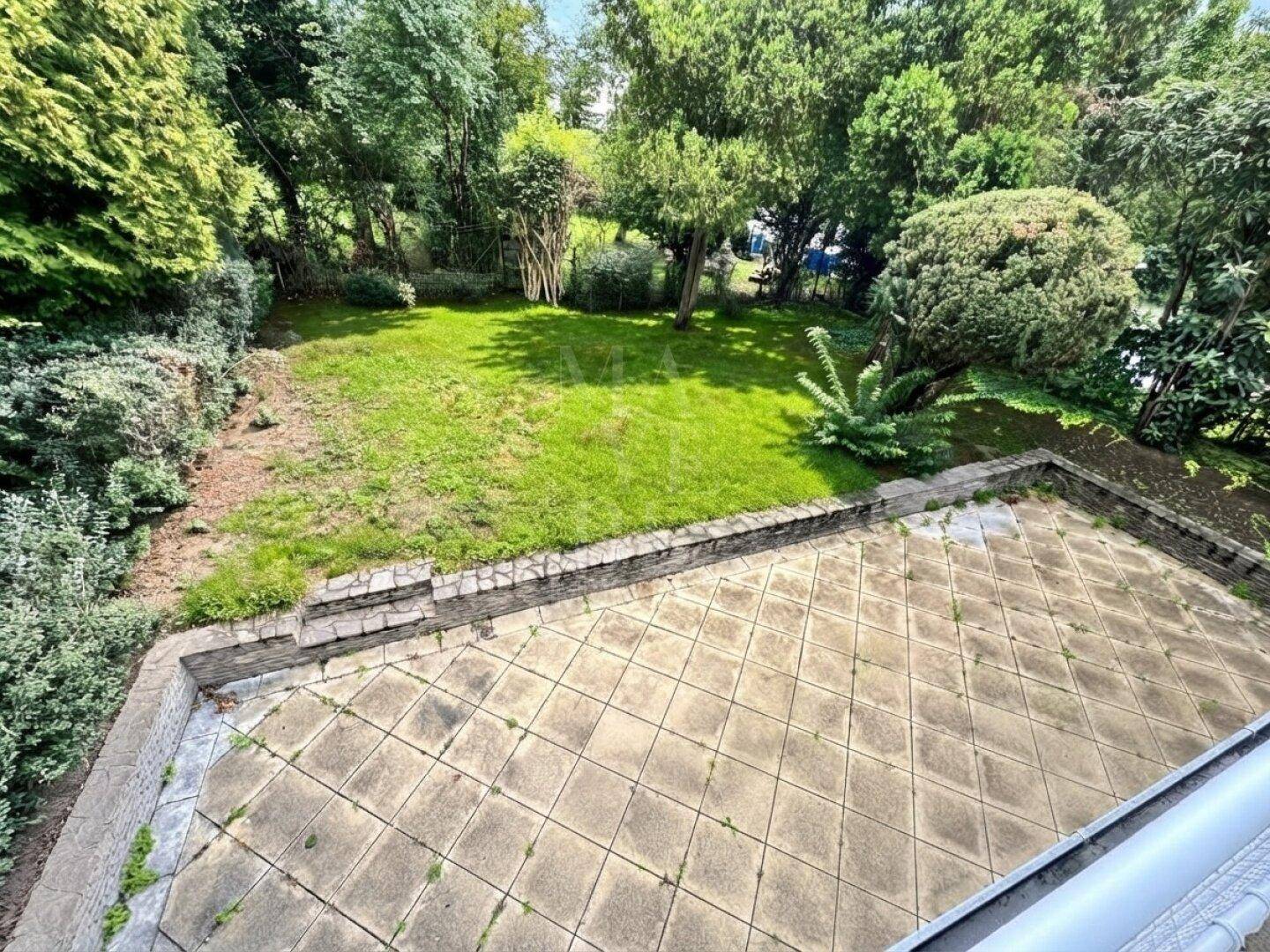 Blick von oben auf den gepflegten Gartenbereich mit Rasenfläche und angrenzender Terrasse.