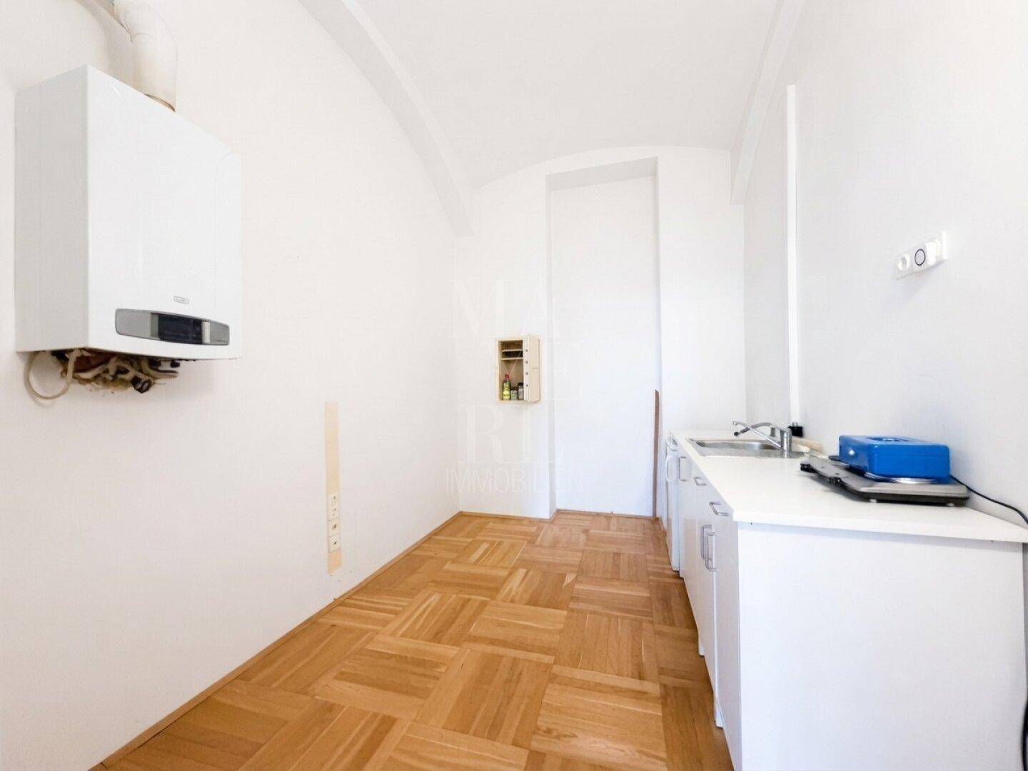 Kleiner Hauswirtschaftsraum mit Gastherme, Spülbecken und einfacher Küchenzeile, ideal für praktische Zwecke.