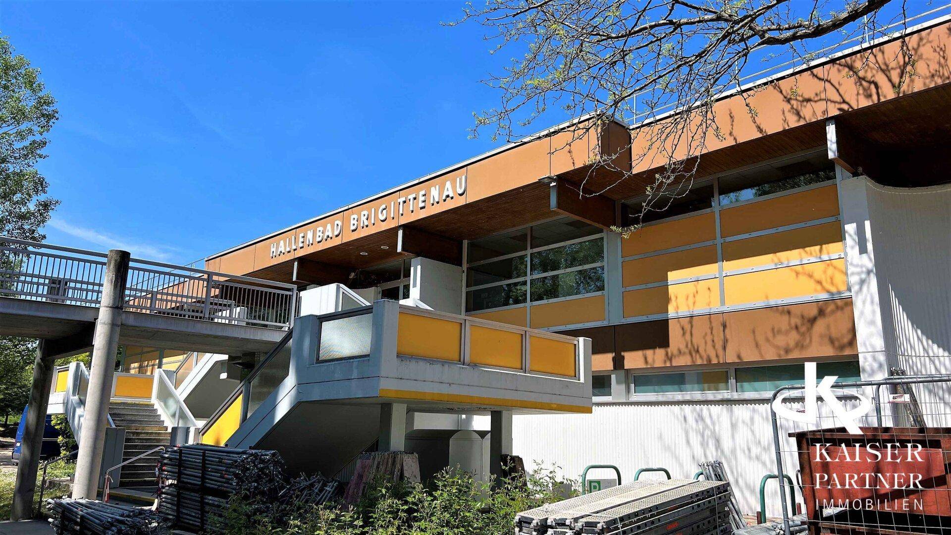 Außenansicht des Hallenbades Brigittenau mit moderner Architektur und gelben Akzenten.