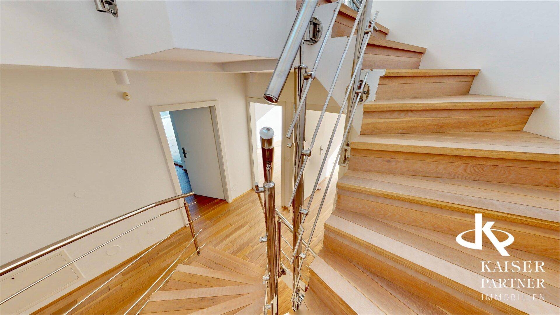 Elegante Holztreppe mit modernem Edelstahlgeländer, die die verschiedenen Etagen verbindet.