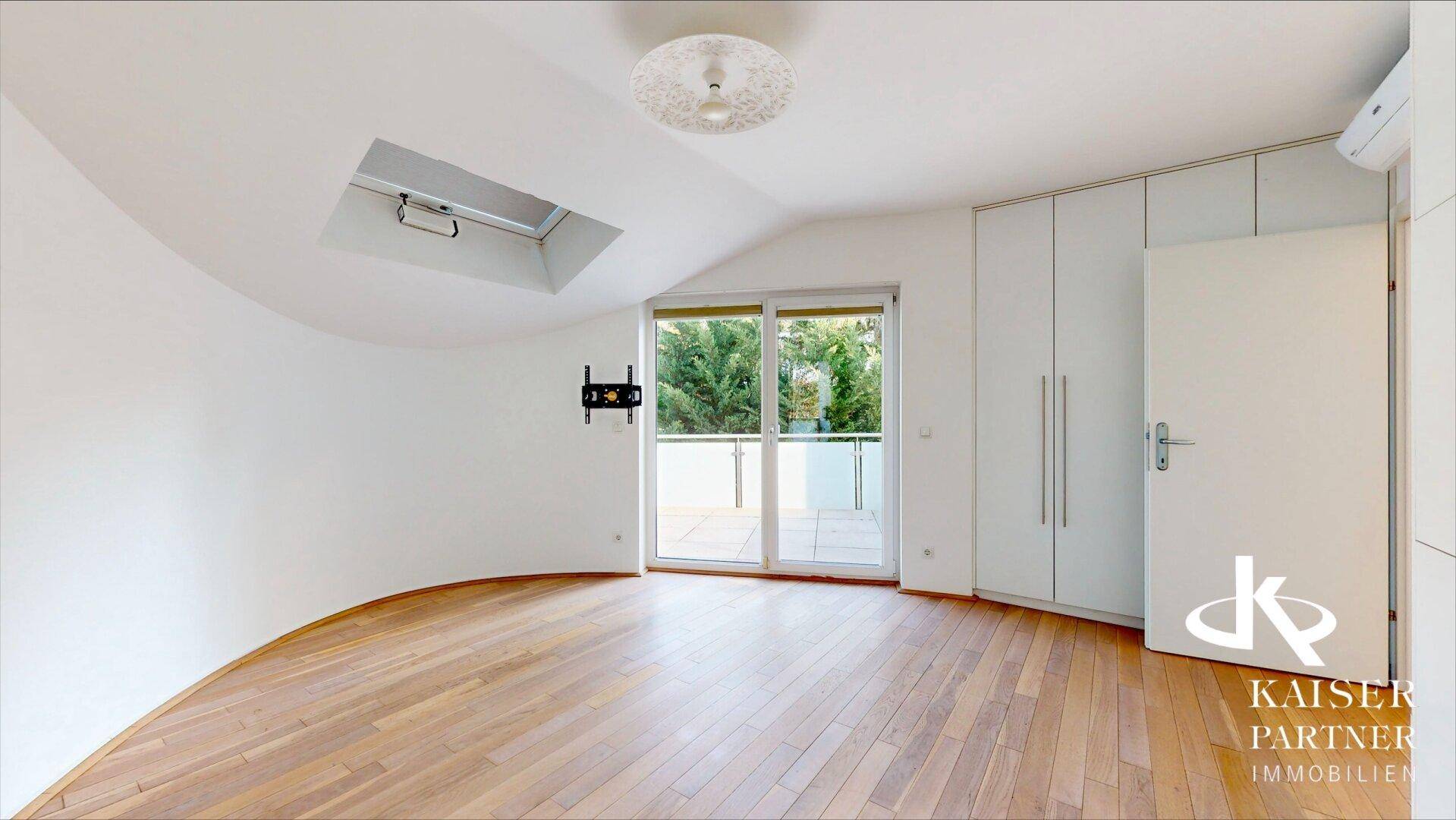 Helles Schlafzimmer mit Holzboden, Einbauschränken, Dachfenster und Zugang zu einem Balkon.
