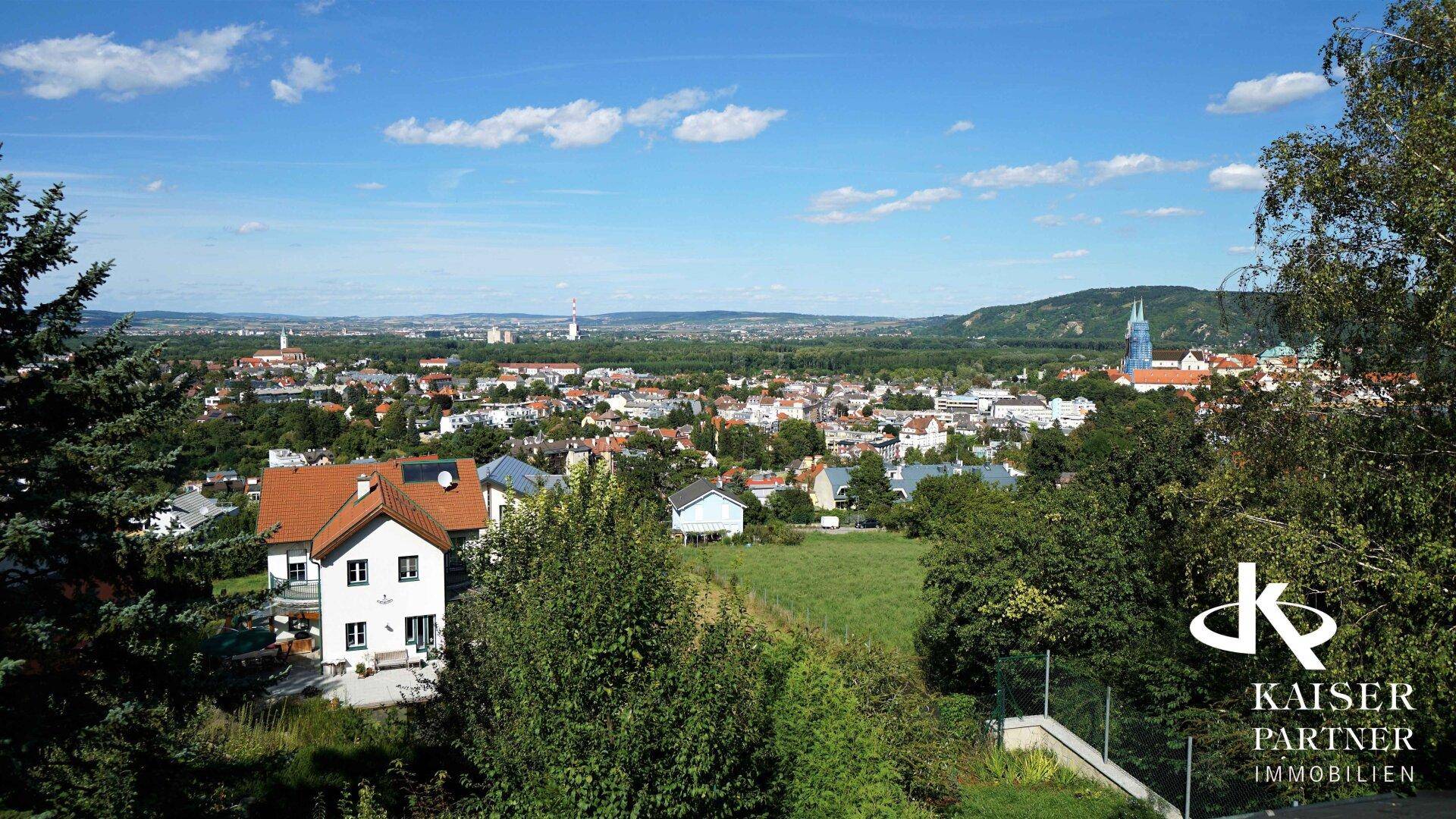 Panoramablick über die Stadt und die weite Landschaft unter einem klaren blauen Himmel.