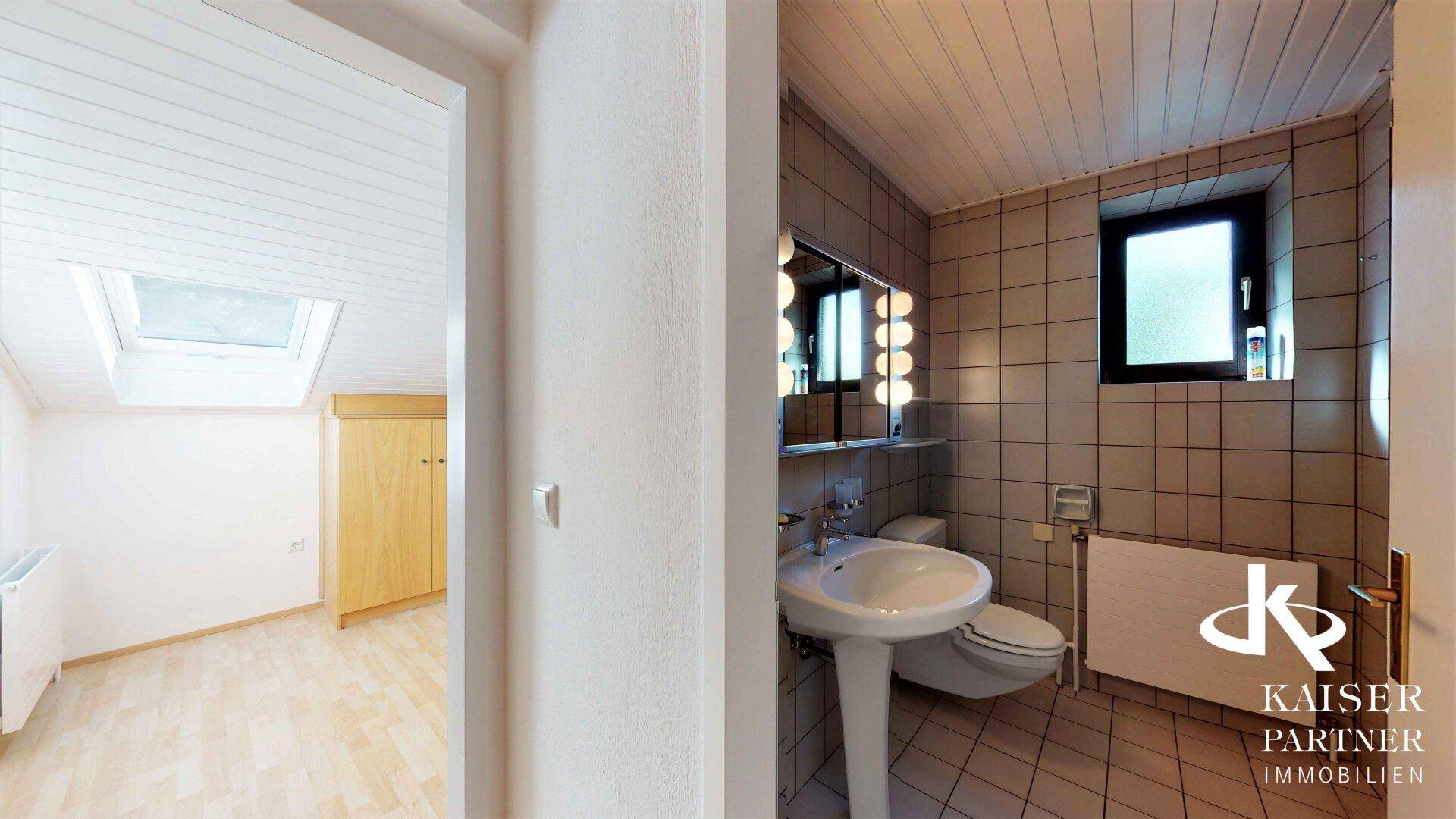 Badezimmer mit Fliesenboden, Waschbecken, Toilette und Fenster, das Tageslicht hereinlässt.