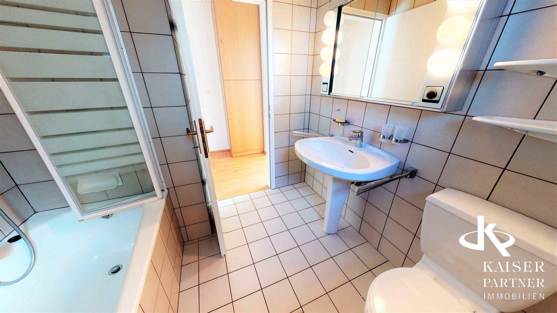Badezimmer mit Badewanne und Duschfunktion, Waschbecken und Toilette, alles in funktionalem Design.