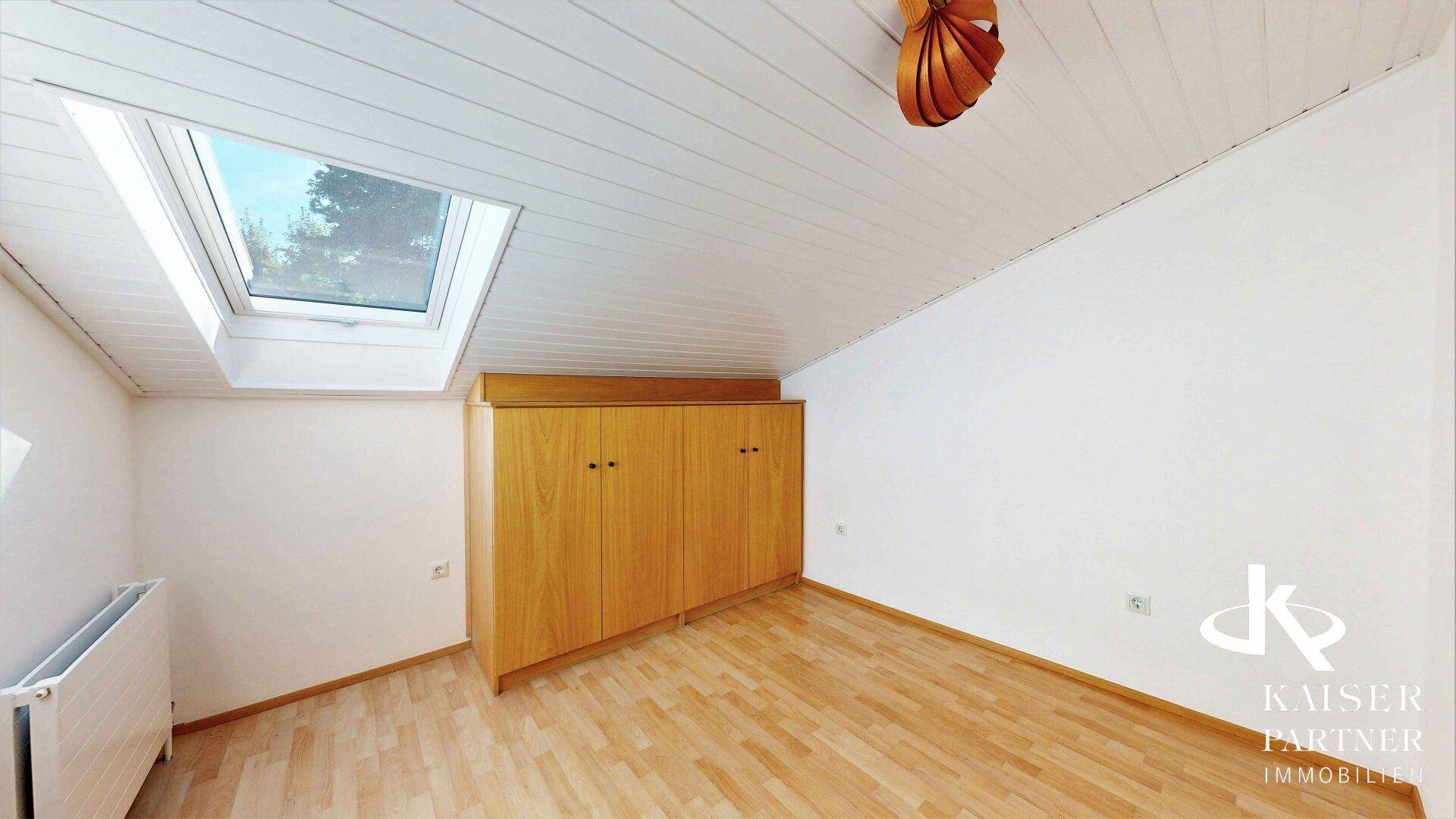 Dachzimmer mit Parkettboden, Dachfenster und einem praktischen Einbauschrank für zusätzlichen Stauraum.
