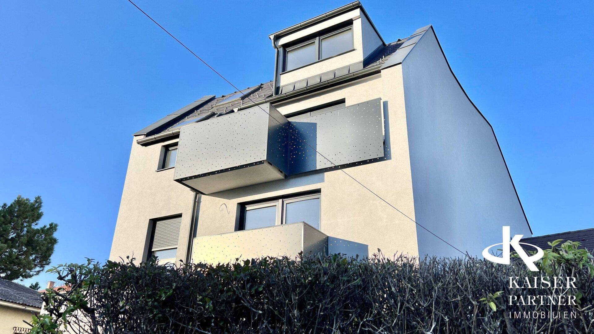 Moderne Gebäudefassade mit Balkonen und großen Fenstern unter klarem Himmel.