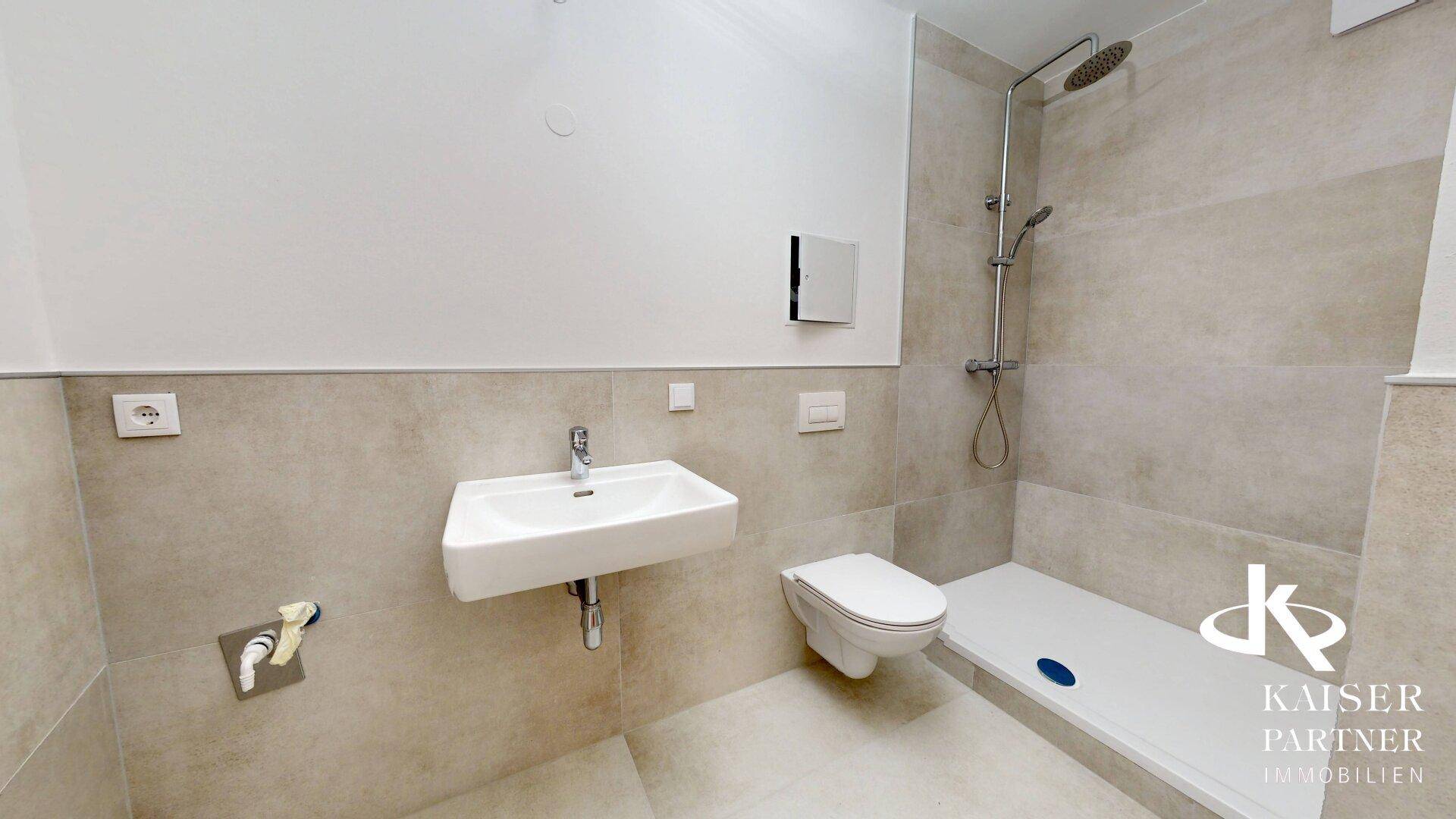 Modernes Badezimmer mit begehbarer Dusche, Wand-WC und hellen Fliesen an Wänden und Boden.