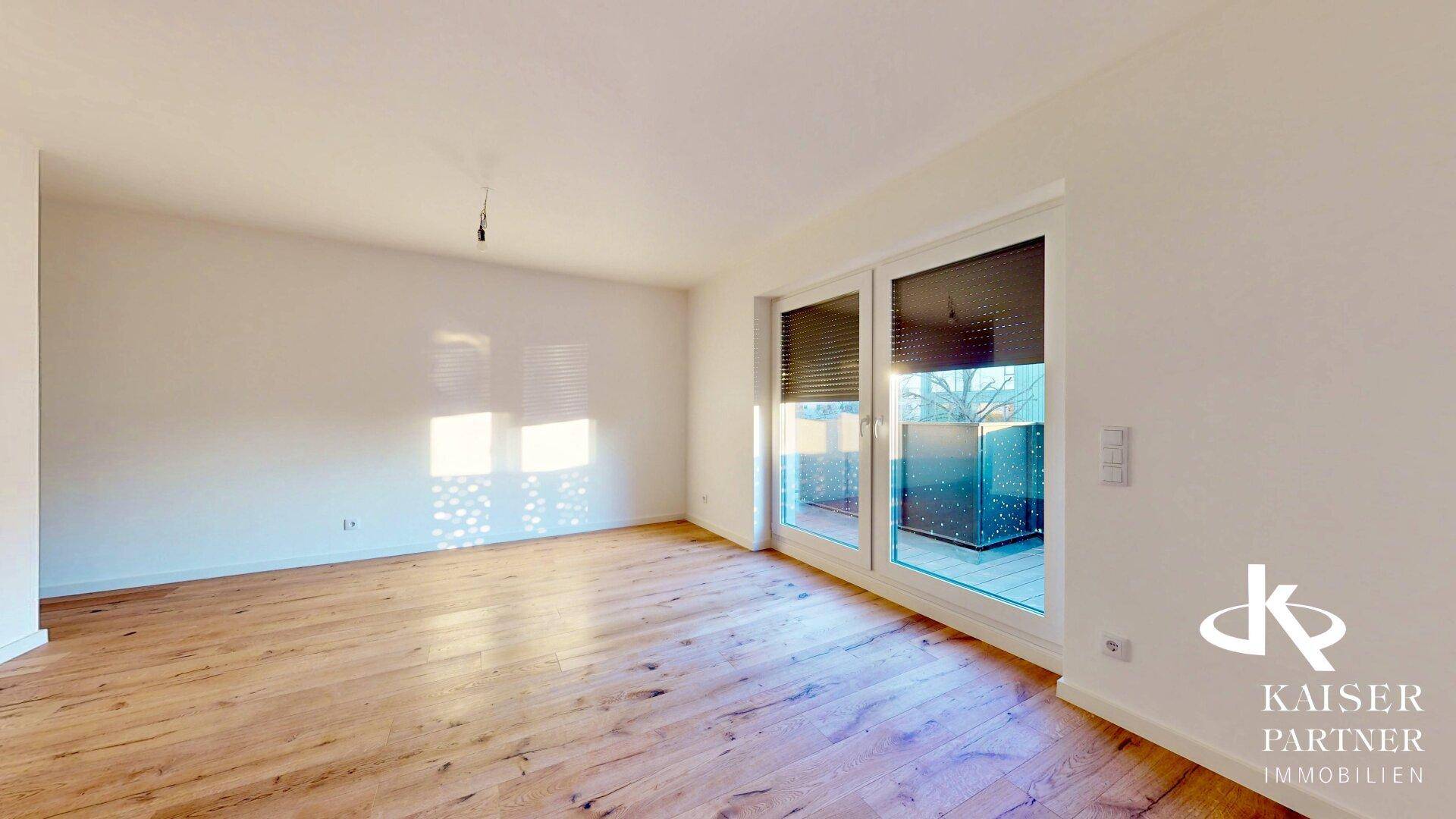 Helles Wohnzimmer mit Holzboden und Zugang zu einem Balkon oder einer Terrasse.
