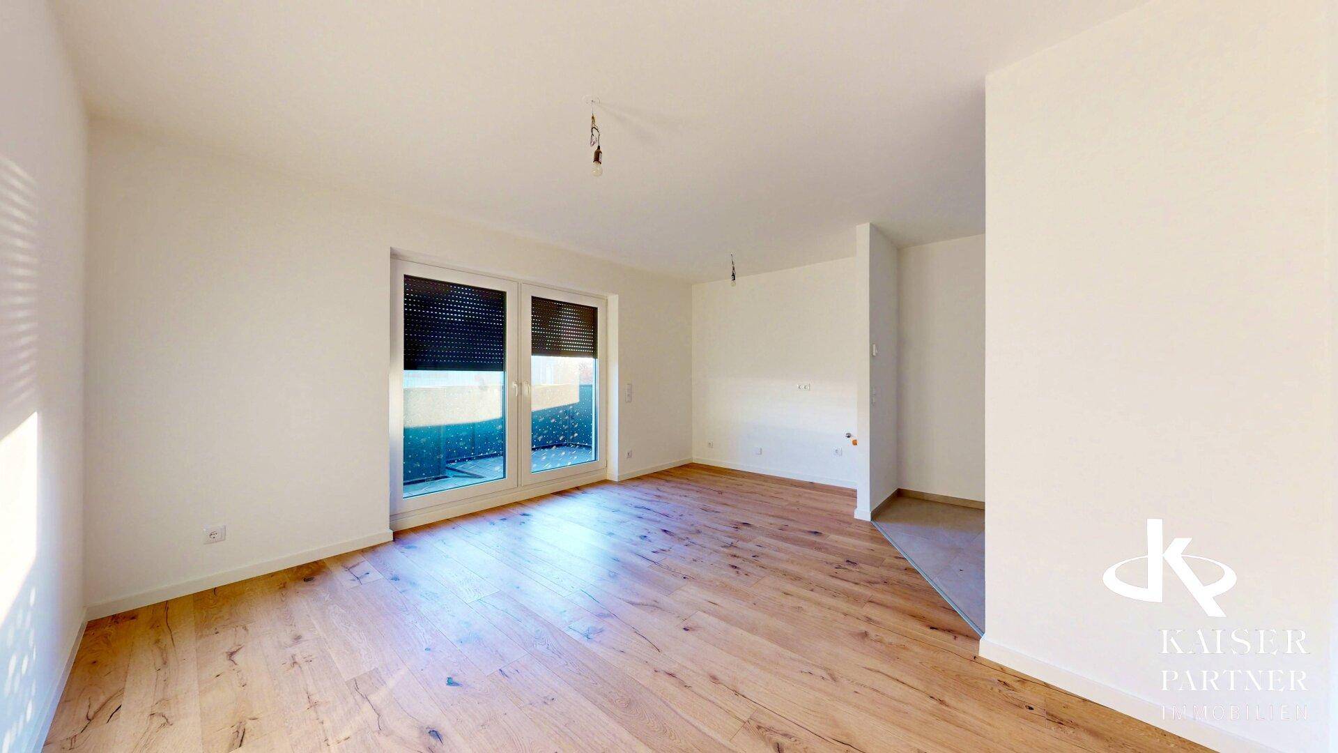 Geräumiger Wohnbereich mit Holzboden und viel Tageslicht durch große Fenster.