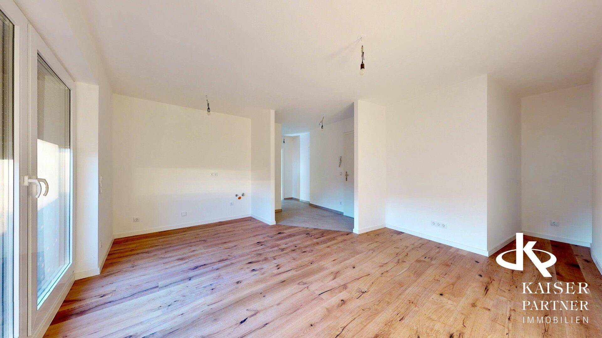 Offener Wohnbereich mit Holzboden und Übergang zu einem Flur, ideal für moderne Einrichtung.