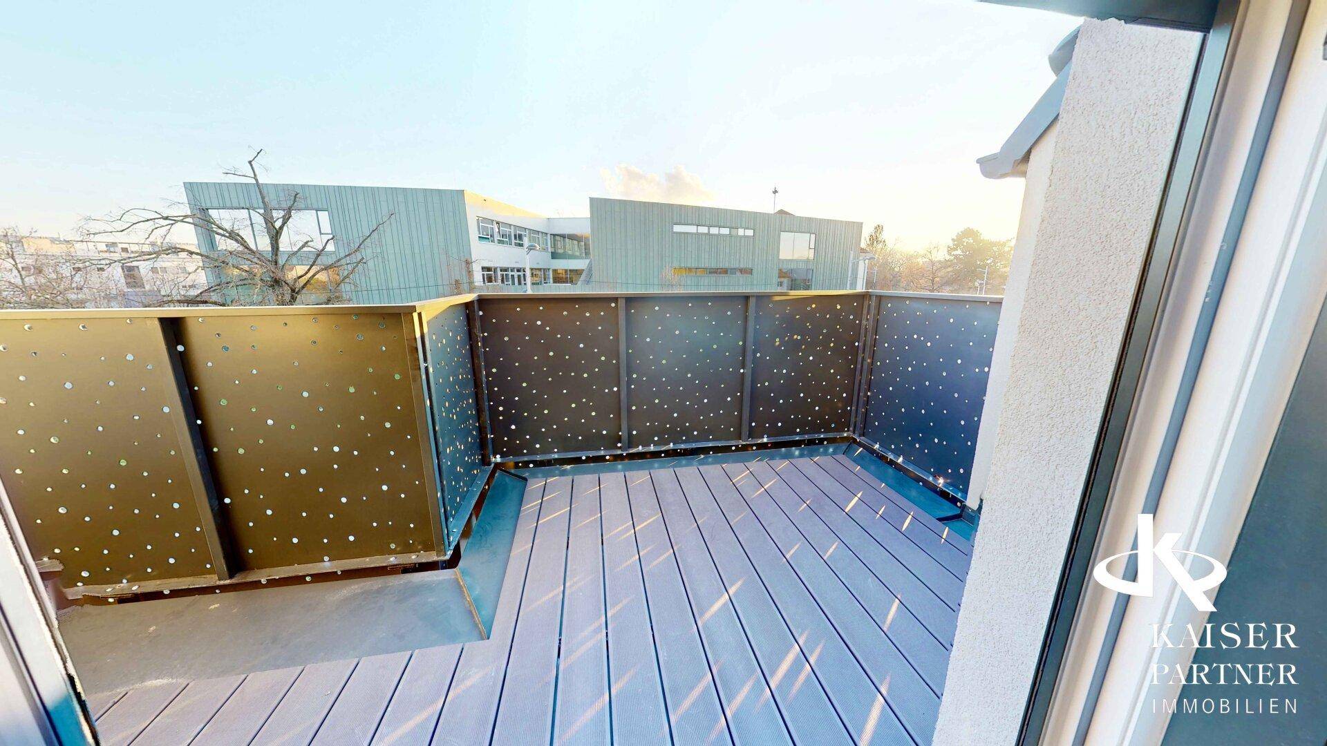 Sonniger Terrassenbereich mit modernem Lochblechgeländer und Blick auf die umliegenden Gebäude.