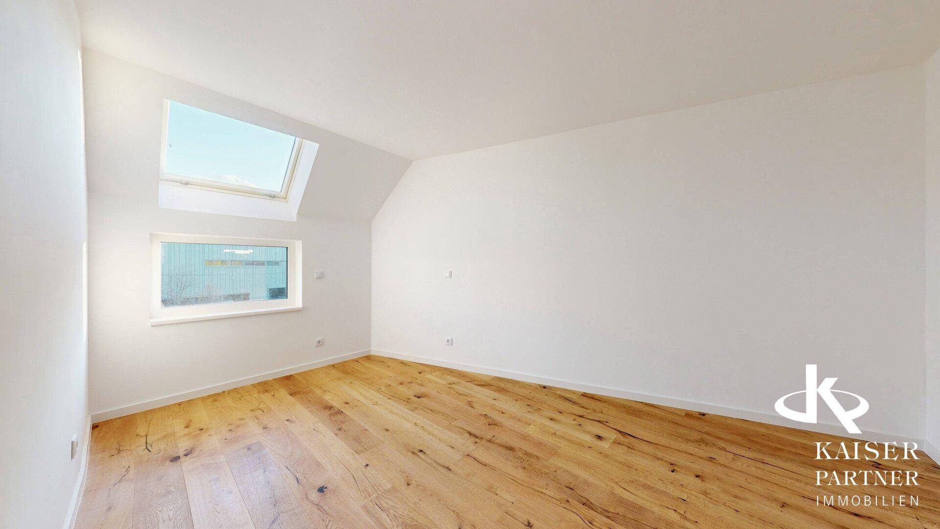Helles Schlafzimmer im Dachgeschoss mit Holzboden, Dachfenster und schrägen Wänden.