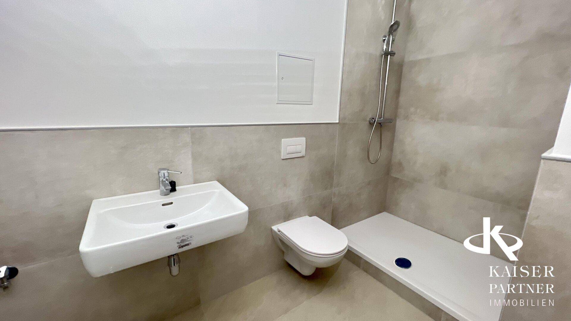 Modernes Badezimmer mit ebenerdiger Dusche, Wand-WC und hellem Fliesenboden.